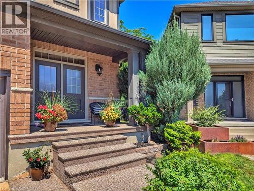 Welcoming entry featuring a brick exterior, double French doors with multiple panes, and a tiered concrete staircase leading to the main entrance - 913 Valebrook Court, Kitchener, ON - Outdoor With Deck Patio Veranda