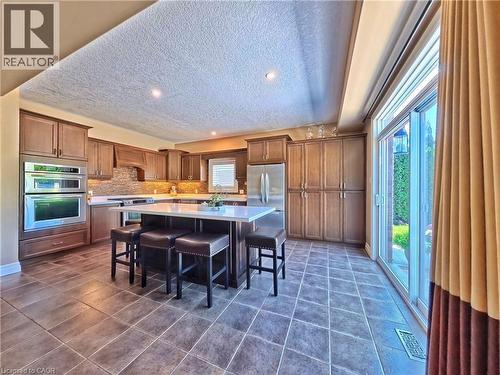 Gourmet kitchen featuring custom wood cabinetry, stainless steel appliances, quartz countertops, and a large center island with seating - 913 Valebrook Court, Kitchener, ON - Indoor