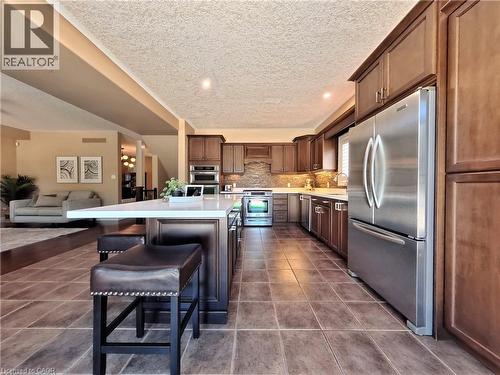 Spacious kitchen featuring an expansive island, stainless steel appliances, wood-finish cabinetry, and tiled flooring - 913 Valebrook Court, Kitchener, ON - Indoor Photo Showing Kitchen With Upgraded Kitchen