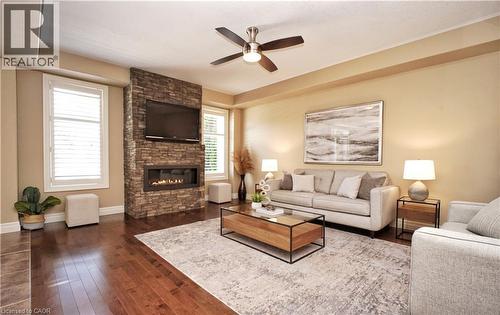 Hardwood flooring throughout, stone-clad fireplace with built-in linear electric insert, and ceiling fan with integrated lighting - 913 Valebrook Court, Kitchener, ON - Indoor Photo Showing Living Room With Fireplace