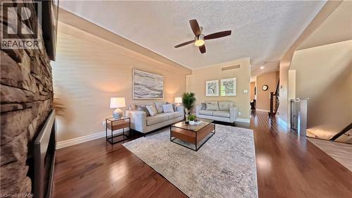 Spacious living room featuring hardwood flooring throughout, a textured stone accent wall, and abundant natural light from multiple windows - 913 Valebrook Court, Kitchener, ON - Indoor Photo Showing Living Room