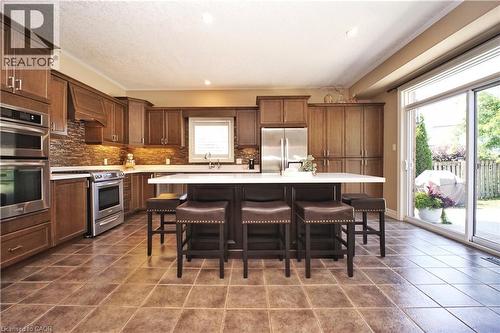 Kitchen featuring wood cabinetry, stainless steel appliances, a center island with countertop, tile flooring, and a sliding glass door - 913 Valebrook Court, Kitchener, ON - Indoor