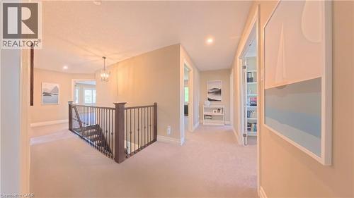 Expansive second-floor landing featuring neutral carpet flooring, recessed lighting, and custom built-in shelving with glass doors - 913 Valebrook Court, Kitchener, ON - Indoor Photo Showing Other Room
