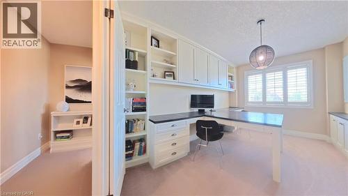 Sophisticated home office featuring built-in cabinetry with shelving and workspace, pendant lighting, desk with integrated storage drawers, ergonomic seating, light wood-finish flooring, and abundant - 913 Valebrook Court, Kitchener, ON - Indoor