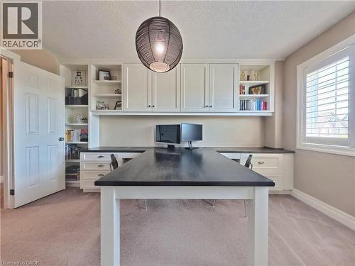 Sophisticated home office featuring a spacious black-topped work island with white base cabinetry, wall-mounted shelving with open storage, recessed lighting, pendant fixture overhead, and abundant na - 913 Valebrook Court, Kitchener, ON - Indoor