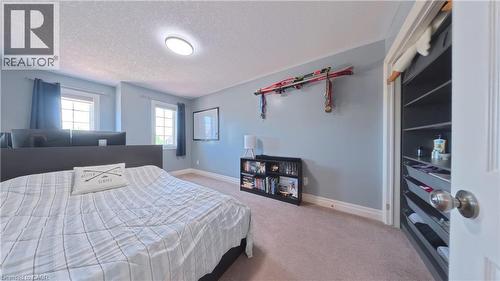 Spacious primary bedroom featuring soft blue walls, dual windows with natural light, recessed ceiling lighting, and direct access to a walk-in closet with built-in shelving and storage - 913 Valebrook Court, Kitchener, ON - Indoor Photo Showing Bedroom