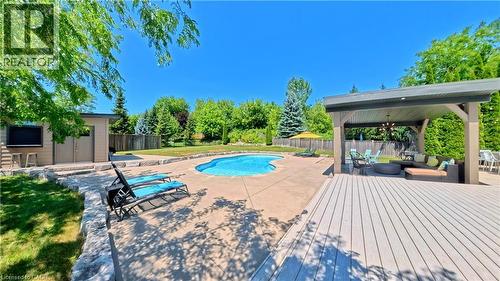 Expansive backyard oasis featuring a resort-style heated swimming pool with integrated spa, composite decking with pergola-covered entertaining area, mature landscaping with established trees, and man - 913 Valebrook Court, Kitchener, ON - Outdoor With In Ground Pool With Deck Patio Veranda With Backyard