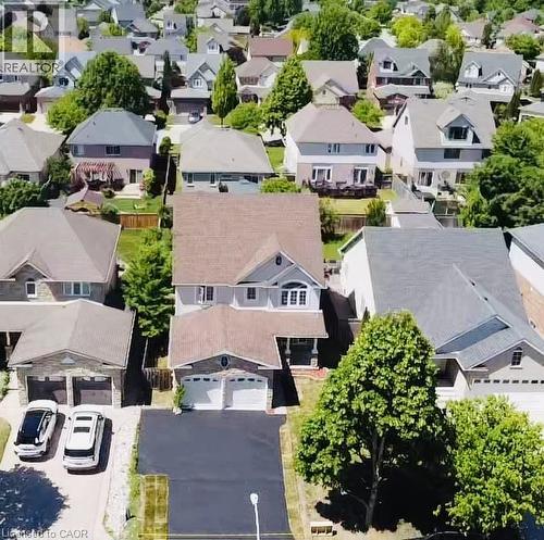 Aerial view showcasing this residential property with a freshly sealed asphalt driveway, two-car garage, composite or architectural shingle roofing, and mature landscaping including established trees - 43 Decaro Crescent, Cambridge, ON - Outdoor With View