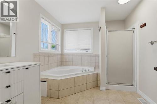 Spa-inspired master bathroom featuring a soaking tub with tile surround, separate walk-in shower enclosure with frameless glass door, dual vanity with black hardware, ceramic tile flooring, and abunda - 43 Decaro Crescent, Cambridge, ON - Indoor Photo Showing Bathroom