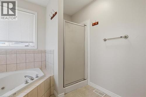 Primary bathroom featuring a soaking tub with dual faucets, a frameless glass-enclosed shower with chrome fixtures, tile surround, ceramic tile flooring, and a large window with blinds providing natur - 43 Decaro Crescent, Cambridge, ON - Indoor Photo Showing Bathroom