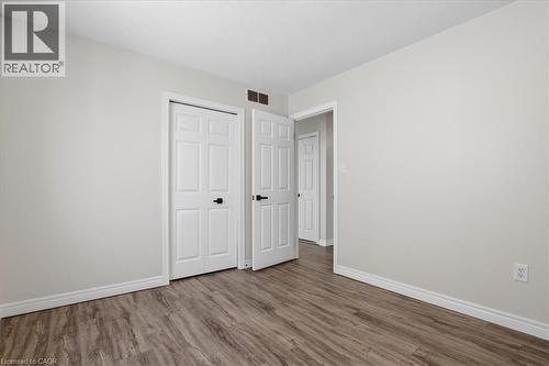 Spacious bedroom featuring warm wood-finish flooring, pristine white six-panel closet doors, and bright natural lighting from recessed ceiling fixtures - 43 Decaro Crescent, Cambridge, ON - Indoor Photo Showing Other Room