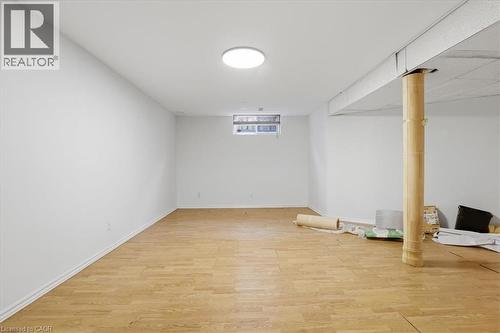 Spacious basement recreation room featuring warm wood-finish flooring, recessed ceiling lighting, and a structural support column - 43 Decaro Crescent, Cambridge, ON - Indoor Photo Showing Other Room