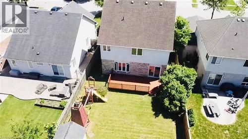 Expansive backyard featuring a manicured lawn, mature trees providing natural shade, a wooden deck with integrated seating area, and direct access from the home's rear elevation - 43 Decaro Crescent, Cambridge, ON - Outdoor