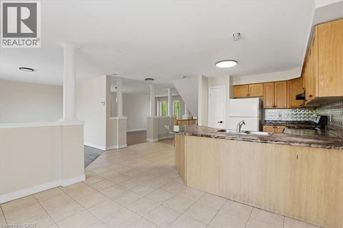 Spacious open-concept kitchen and dining area featuring wood-finish cabinetry, tile flooring, granite countertops, and stainless steel appliances - 43 Decaro Crescent, Cambridge, ON - Indoor Photo Showing Kitchen