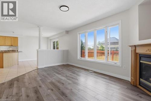 Bright open-concept living space featuring wood-finish flooring, abundant natural light from multi-panel sliding glass doors, and a fireplace with wood surround - 43 Decaro Crescent, Cambridge, ON - Indoor With Fireplace