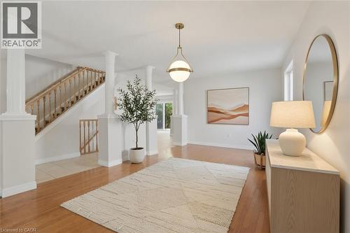 Welcoming foyer showcasing gleaming wood-finish flooring, a geometric area rug, and a wooden staircase with turned balusters - 43 Decaro Crescent, Cambridge, ON - Indoor Photo Showing Other Room