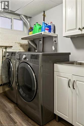 Laundry area featuring wood-finish flooring, white cabinetry, and a utility sink - 23 Kipling Road, Hamilton, ON - Indoor Photo Showing Laundry Room