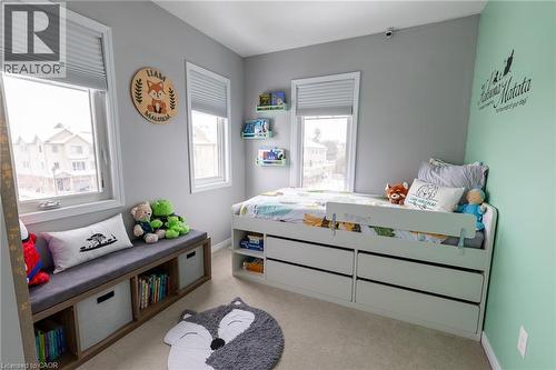 Bright, light-filled bedroom featuring multiple windows with cellular shades, soft mint accent wall, built-in storage bed with integrated drawers, and a wood-finish storage bench with cushioned seatin - 750 Lawrence Street Unit# 86, Cambridge, ON - Indoor Photo Showing Bedroom