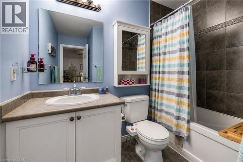 Bathroom featuring a white vanity with paneling and dark hardware, a spacious countertop, an oval undermount sink, a white toilet, and a shower-over-tub combination with dark tile surround and decorat - 750 Lawrence Street Unit# 86, Cambridge, ON - Indoor Photo Showing Bathroom
