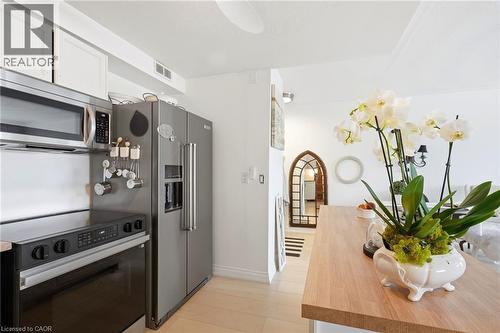 Stainless steel appliances, wood-finish flooring, white cabinetry, and a wood-finish countertop - 8 Woodman Drive S Unit# 708, Hamilton, ON - Indoor