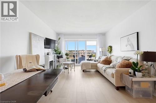 Light wood-finish flooring, white walls, and glass sliding doors leading to an outdoor balcony - 8 Woodman Drive S Unit# 708, Hamilton, ON - Indoor Photo Showing Living Room