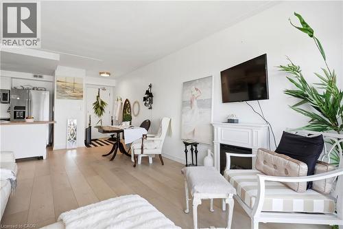 Light wood-finish flooring throughout, white walls, and a fireplace with a white mantel - 8 Woodman Drive S Unit# 708, Hamilton, ON - Indoor