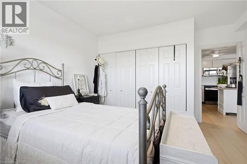 White painted walls, wood-finish flooring, and white bi-fold closet doors - 8 Woodman Drive S Unit# 708, Hamilton, ON - Indoor Photo Showing Bedroom