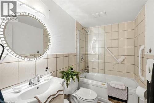 Bathroom featuring a single basin vanity, illuminated mirror, and a bathtub with a shower and glass partition - 8 Woodman Drive S Unit# 708, Hamilton, ON - Indoor Photo Showing Bathroom