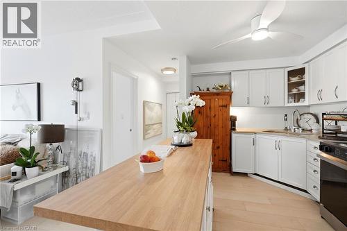 Kitchen featuring a ceiling fan with integrated lighting, white cabinetry, light countertops, and wood-finish flooring - 8 Woodman Drive S Unit# 708, Hamilton, ON - Indoor Photo Showing Kitchen