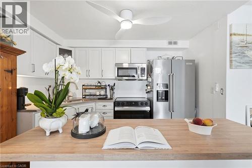 Kitchen featuring a wood-finish island, white cabinetry, stainless steel appliances, and a ceiling fan - 8 Woodman Drive S Unit# 708, Hamilton, ON - Indoor Photo Showing Kitchen With Stainless Steel Kitchen