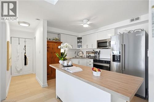 Kitchen featuring white cabinetry, stainless steel appliances, a wood-finish countertop on the island, and light wood-finish flooring - 8 Woodman Drive S Unit# 708, Hamilton, ON - Indoor Photo Showing Kitchen With Stainless Steel Kitchen