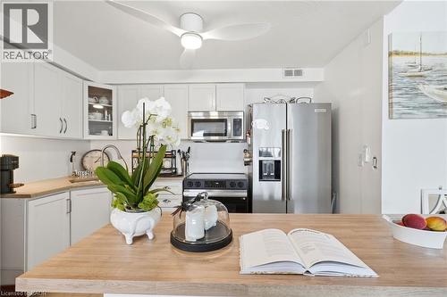White cabinetry, stainless steel appliances, wood-finish countertops, built-in microwave, and ceiling fan - 8 Woodman Drive S Unit# 708, Hamilton, ON - Indoor Photo Showing Kitchen With Stainless Steel Kitchen