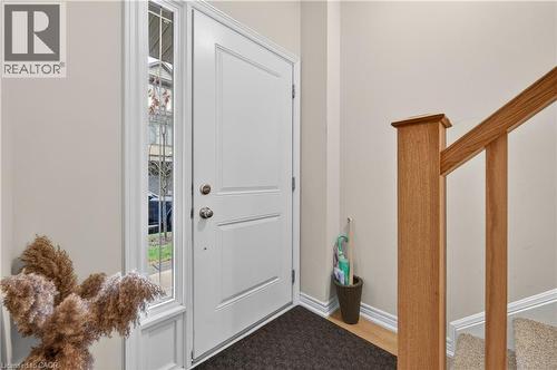 White paneled entry door with sidelight, wood-finish flooring, and natural wood staircase newel post and handrail - 19 Picardy Drive Unit# 13, Hamilton, ON - Indoor Photo Showing Other Room