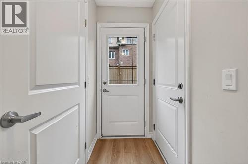 White interior doors with panel detailing, wood-finish flooring, and a glass-paneled exterior door - 19 Picardy Drive Unit# 13, Hamilton, ON - Indoor Photo Showing Other Room