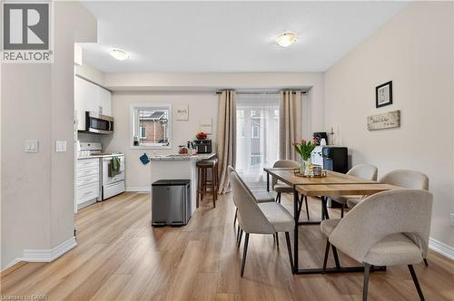 Open-concept living space with wood-finish flooring, white cabinetry, a built-in microwave, and a dining area with natural light - 19 Picardy Drive Unit# 13, Hamilton, ON - Indoor