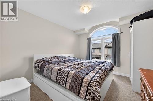 Arched window with casing, neutral wall finishes, textured carpeting, and ceiling-mounted light fixture - 19 Picardy Drive Unit# 13, Hamilton, ON - Indoor Photo Showing Bedroom