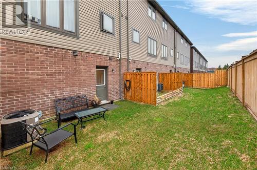 Expansive grassy area featuring a full privacy fence, brick exterior, and an exterior door - 19 Picardy Drive Unit# 13, Hamilton, ON - Outdoor