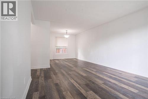 Spacious interior room showcasing rich wood-finish flooring with varied plank toning, bright natural light from a multi-pane window, clean white walls, and ceiling-mounted lighting fixture - 695 Glen Forrest Boulevard Unit# Upper, Waterloo, ON - Indoor Photo Showing Other Room