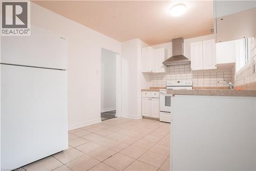 Kitchen with tile flooring, white cabinetry, a stainless steel range hood, and light-toned countertops - 695 Glen Forrest Boulevard Unit# Upper, Waterloo, ON - Indoor Photo Showing Kitchen