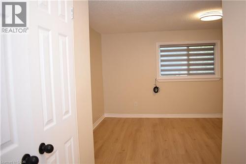 Wood-finish flooring with white baseboards, a window with horizontal blinds, and a flush-mount ceiling light fixture - 655 Albert Street Unit# A, Waterloo, ON - Indoor Photo Showing Other Room