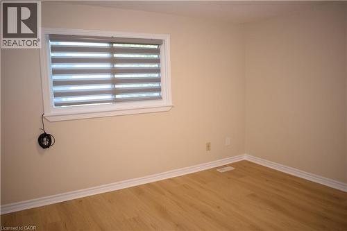 Light-toned walls with wood-finish flooring, featuring a window with layered shades and white trim - 655 Albert Street Unit# A, Waterloo, ON - Indoor Photo Showing Other Room