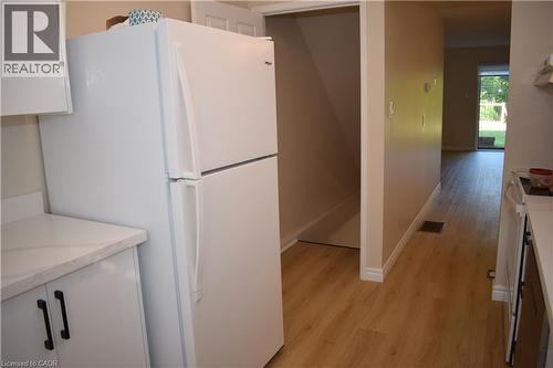 White kitchen cabinetry with black hardware, light-toned countertops, wood-finish flooring, and a white refrigerator - 655 Albert Street Unit# A, Waterloo, ON - Indoor