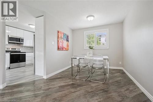Wood-finish flooring, white window shutters, ceiling-mounted light fixture, and a kitchen featuring stainless steel appliances and glossy white cabinetry - 60 Elmsdale Drive Unit# 25, Kitchener, ON - Indoor