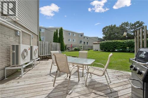 Wood-finish deck with a stone exterior wall and a manicured lawn - 60 Elmsdale Drive Unit# 25, Kitchener, ON - Outdoor With Deck Patio Veranda With Exterior