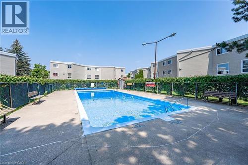 Outdoor swimming pool with concrete surround - 60 Elmsdale Drive Unit# 25, Kitchener, ON - Outdoor With In Ground Pool With Backyard