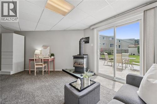 Sliding glass doors opening to an exterior wood deck, a freestanding wood-burning stove with a glass door, light grey wall paint, and recessed ceiling lighting - 60 Elmsdale Drive Unit# 25, Kitchener, ON - Indoor