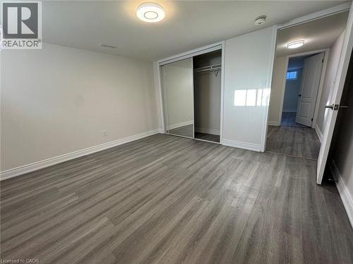 Grey wood-finish flooring, white walls, flush mount ceiling lighting, and sliding mirrored closet doors - 15 Pinecrest Drive Unit# Lower, Kitchener, ON - Indoor Photo Showing Other Room