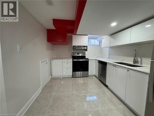 Recessed lighting illuminates the kitchen featuring a stainless steel appliance suite, white cabinetry, integrated sink, and light-toned tile flooring - 15 Pinecrest Drive Unit# Lower, Kitchener, ON - Indoor Photo Showing Kitchen With Double Sink