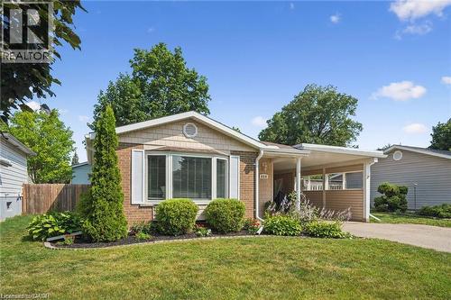 Charming brick ranch home featuring a covered front porch, expansive picture windows with contemporary framing, manicured landscaping with mature trees and established plantings, a wide driveway, and - 659 Glen Forrest Boulevard, Waterloo, ON - Outdoor