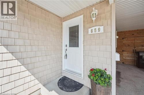 Welcoming entry featuring crisp white-painted door with glass panel, ceramic tile exterior walls in neutral tones, decorative wall-mounted lighting fixture, and potted greenery accent - 659 Glen Forrest Boulevard, Waterloo, ON - Indoor Photo Showing Bathroom